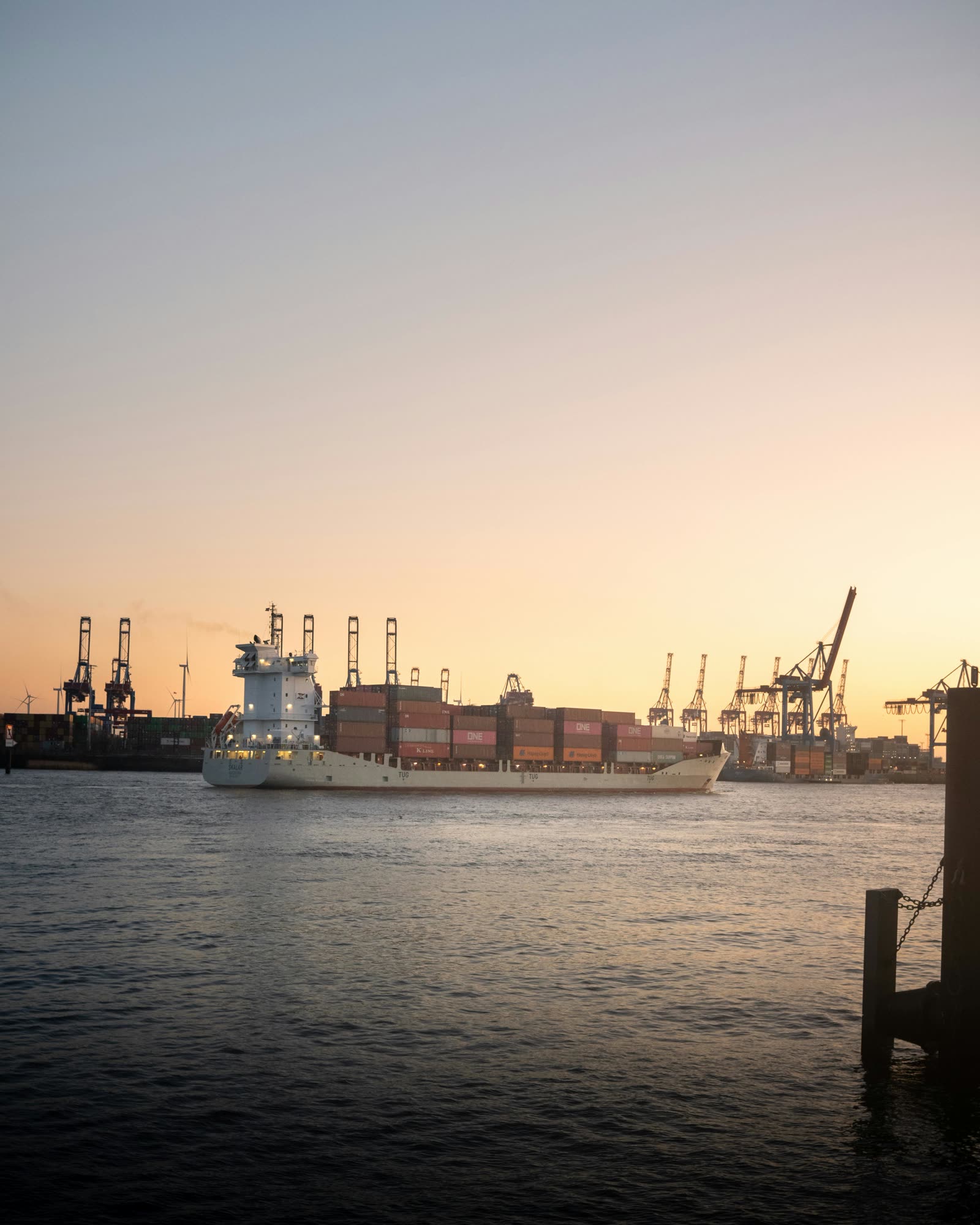Container ship departing a port at sunset
